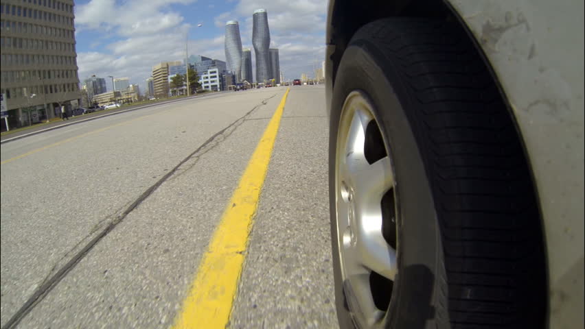 Vehicle Wheel Shot Day 1. Front left tire on a car driving down a city street in