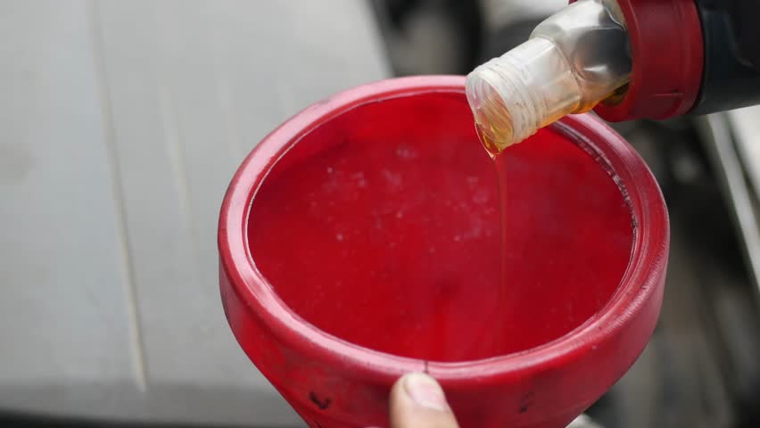 Pouring Liquid Into Red Funnel For Engine Maintenance