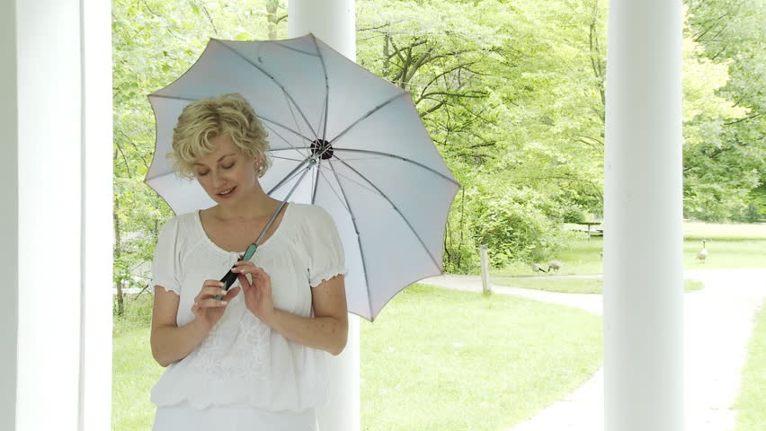 Medium shot of a blonde girl with a blue silk parasol or umbrella in bright