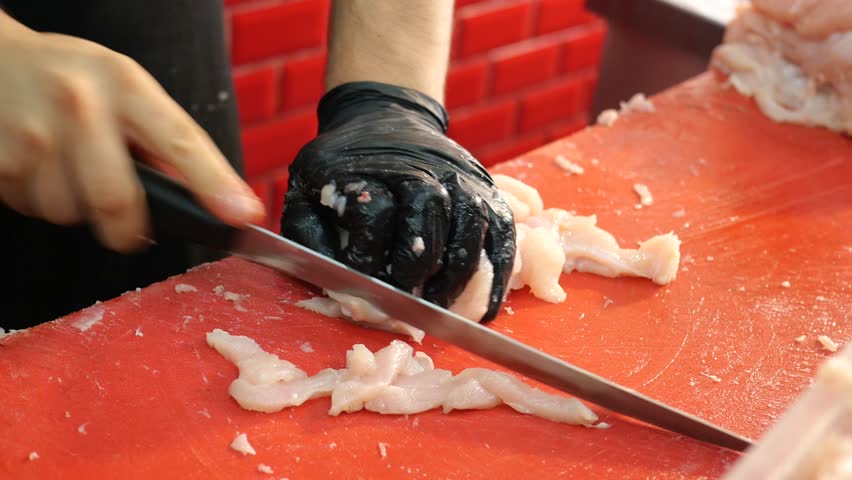 Chef Preparing Fresh Poultry on Red Cutting Board in a Kitchen Setting