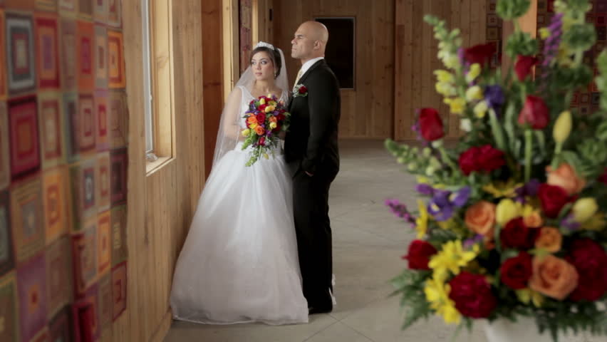 Rack focus from flowers to bride and groom with a dolly shot, tracking to the