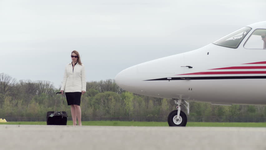 Smartly dressed young woman walks towards a private jet Wide shot starts from