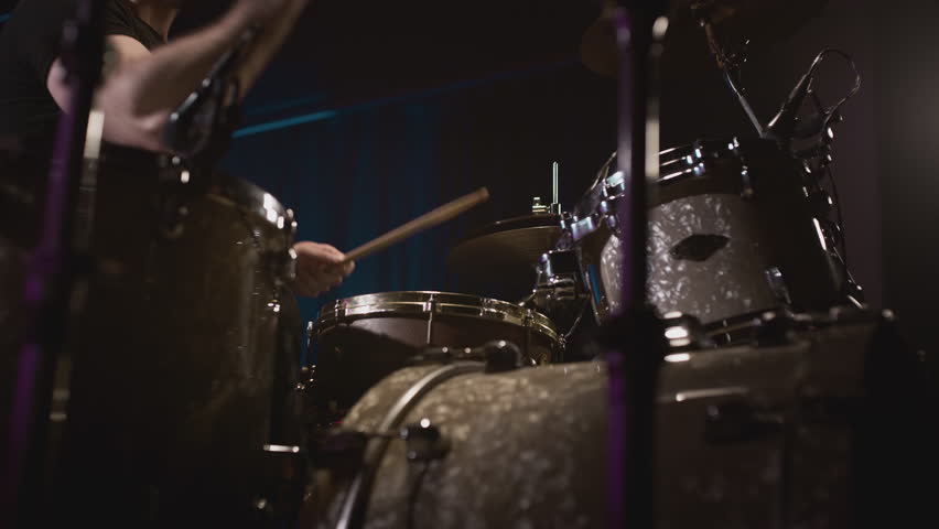 a young attractive guy plays a drum kit. Strikes a cymbal, rehearses. Performance of a rock band, hobby. A man is learning music. Male professional holds drumsticks in hands. Drum set in slow motion