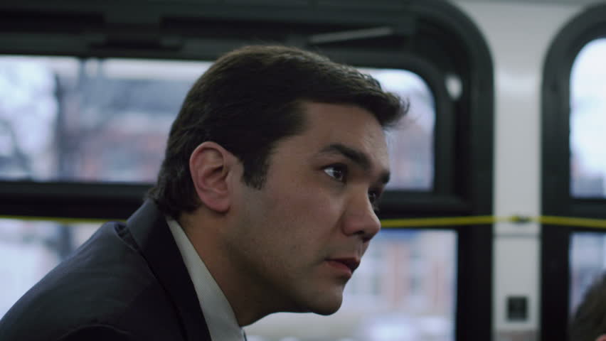 Man in a suit, riding the bus and looking for his stop. Close up.