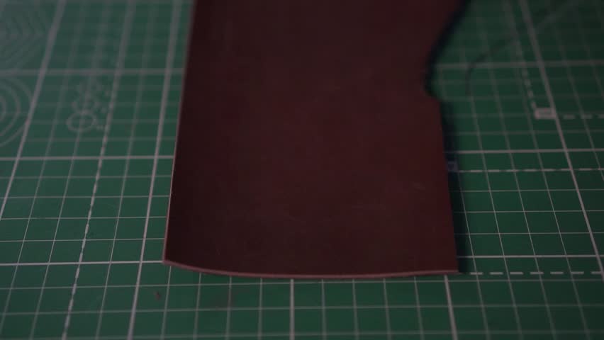 A leather craftsman puts a stamp on the finished product 