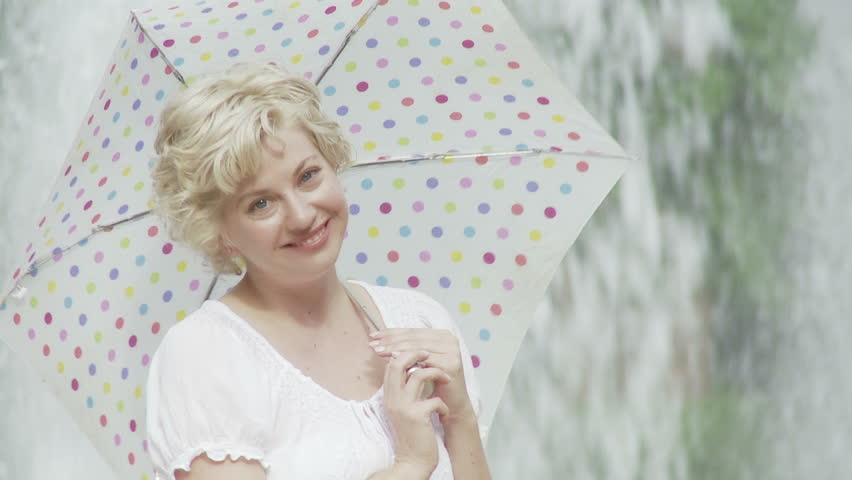Close up of attractive blonde posing with an umbrella in front of a fountain.