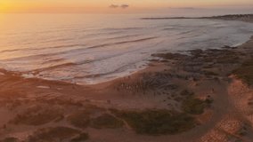 Playa Grande Beach at sunrise, beach party, golden hues over ocean, waves crashing on shore, Punta del Diablo, Uruguay. Aerial drone view - Powered by Shutterstock - Get 15% off with code: PIKWIZARD15