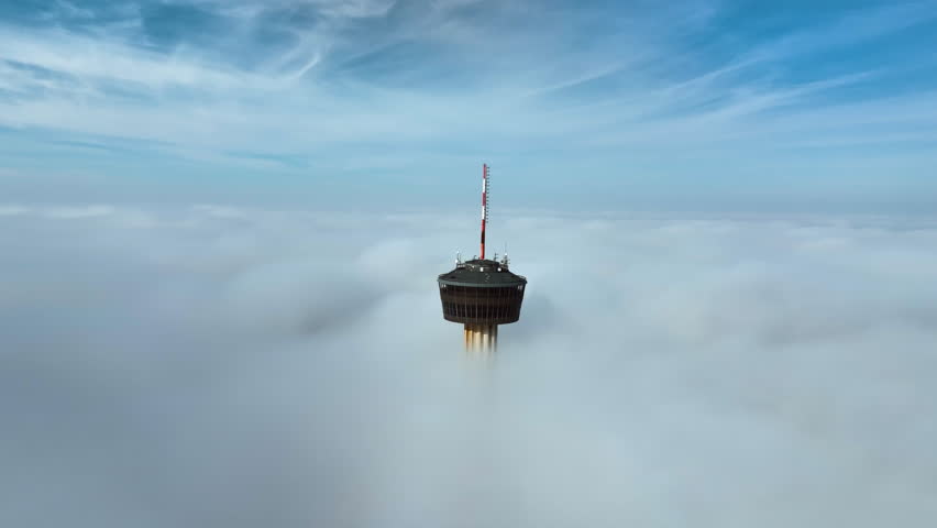 Panoramic drone shot orbiting the Tower of the Americas, misty day in San Antonio