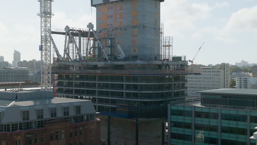 A wide-angle view of a high-rise construction site in Sydney, with workers scattered across multiple levels, capturing the city’s ongoing urban development.