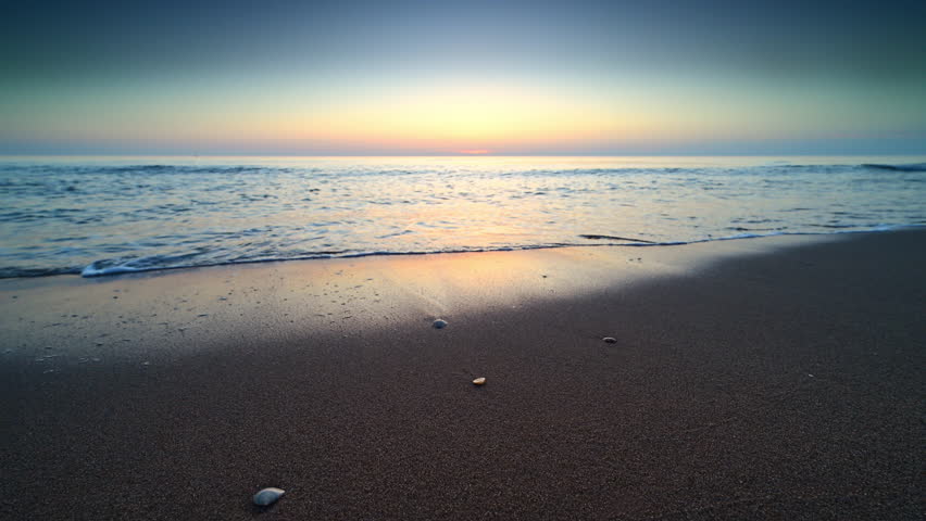 Sunset at the North Sea beach during a calm day in South Holland with gentle waves hitting the sandy beach in The Netherlands.