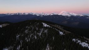 Aerial view of breathtaking mountain landscape at dawn, featuring snow-capped peaks against pastel pink and blue sky in the morning. Dense, dark forests cover the lower slopes. Carpathians, Ukraine. - Powered by Shutterstock - Get 15% off with code: PIKWIZARD15