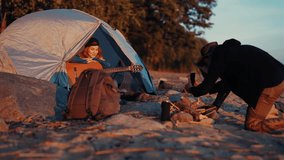 Woman tourist playing guitar in camping tent, man filming video for memories. Merry summer weekend, travelers resting in camp on sea shore, loving couple having fun in nature in vacation trip, tourism - Powered by Shutterstock - Get 15% off with code: PIKWIZARD15