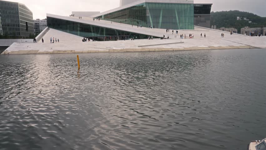 Modern architecture of Oslo Opera House in Norway with people walking on the sloping roof