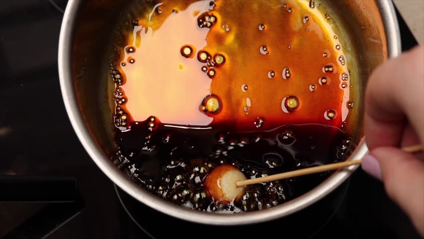 Caramelizing sugar in a saucepan with wooden skewer, cooking process for dessert preparation