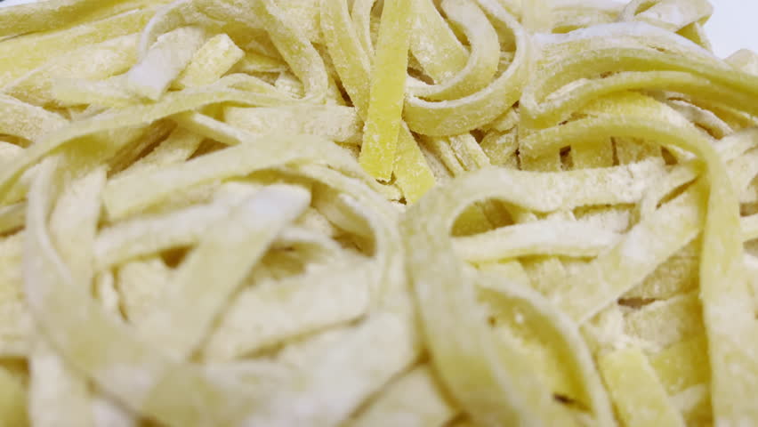 Fresh homemade Italian pasta called tagliatelle sprinkled with flour, noodles ready for cooking, mediterranean cuisine concept