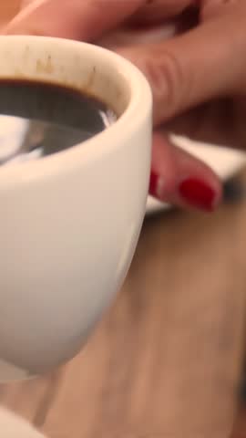 Closeup of a young woman savoring a coffee at a cafe, with a big mug in hand, embodying relaxation and pleasure.