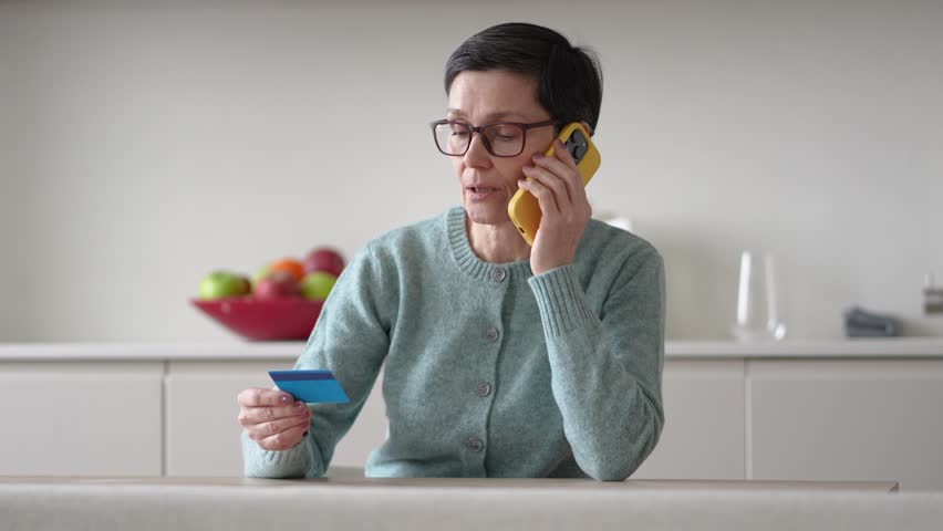 Anxious scared vulnerable woman sending money from accounts to fraudsters on phone. Financial scam, credit card manipulation, identity theft, phone fraud, deception, confusion and exploitation