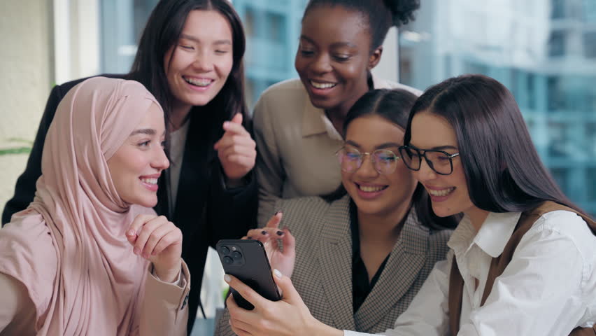 Excited joyful happy multiethnic women females diversity team five girls coworkers businesswomen business colleagues looking mobile phone discussing online app startup shopping social media in office - Powered by Shutterstock - Get 15% off with code: PIKWIZARD15