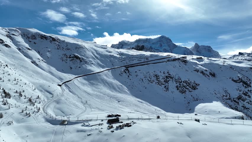Aerial drone footage of Gornergrat bahn railway running towards summit station with Matterhorn mountain peak background in Zermatt on a sunny winter day. Swiss Alps, Switzerland travel journey trip