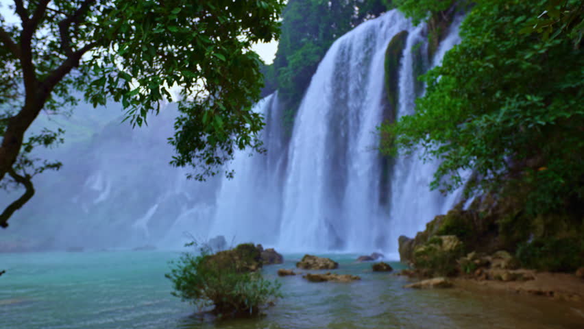 A serene twilight scene featuring cascading the great Ban Gioc Waterfall surrounded by lush greenery. the sky transitions from day to dusk, creating a peaceful and atmospheric moment in nature.