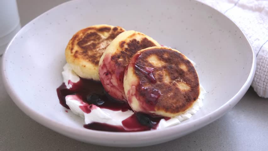 Cottage cheese pancakes with jam, sour cream and nuts.