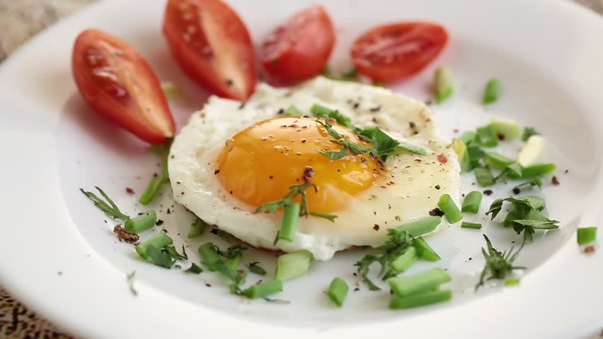 Fried eggs with cherry tomatoes and greens for breakfast.