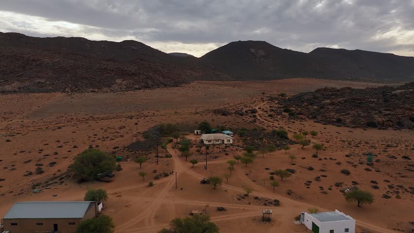 Aerial pulls out from small group of homes in inhospitable desert sand