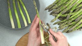 Cook asparagus. Peel and fry green sprouts. Vegetable healthy food. Hands peeling asparagus. Frying pan and plate - Powered by Shutterstock - Get 15% off with code: PIKWIZARD15
