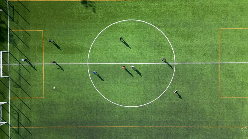 Top-down view of a football training session on a green field with players and equipment visible