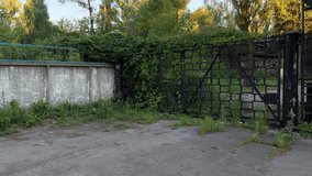Abandoned Industrial Zone Gate Overgrown with Vegetation, Derelict Factory Entrance with Rusty Metal Fence, Urban Decay in Former Manufacturing Area, Neglected Security Checkpoint with Wild Plants - Powered by Shutterstock - Get 15% off with code: PIKWIZARD15