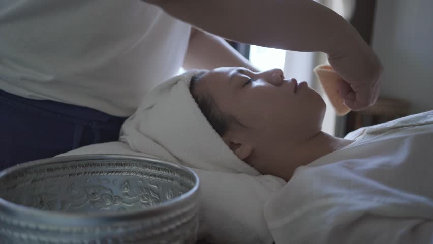 A woman is getting a facial treatment. The woman is smiling and relaxed