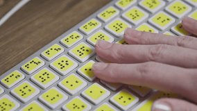 Close-up of a computer keyboard with braille. A blind girl is typing words on the buttons with her hands. Technological device for visually impaired people. Tactilely touches bumps on the keys - Powered by Shutterstock - Get 15% off with code: PIKWIZARD15