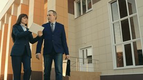 Business people man woman communicating, discussing business, teamwork. Partners, businesswoman, successful cooperation, urban lifestyle. Businessmen in suits talking, leaving office building.Tablet - Powered by Shutterstock - Get 15% off with code: PIKWIZARD15