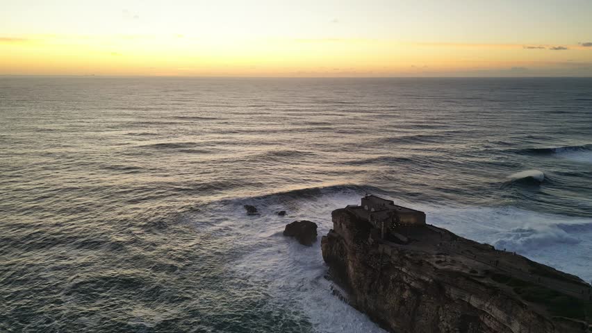 The coastline near farol de nazaré in portugal, showcasing the waves, aerial view
