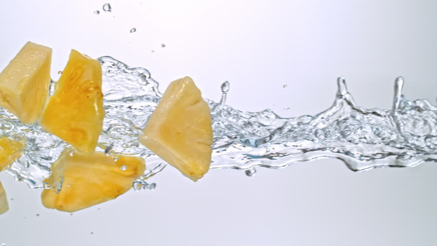 Super Slow Motion of Pineapple Slices Flying with Splashing Water at 1000fps on White Background.