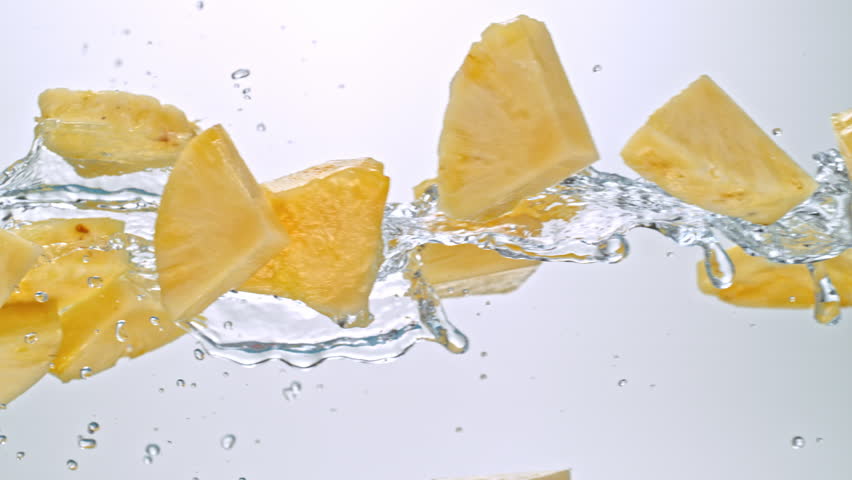 Super Slow Motion of Pineapple Slices Flying with Splashing Water at 1000fps on White Background.