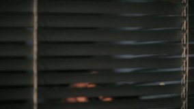 A hand gently parts window blinds, revealing a glimpse of the outside world. The setting suggests a quiet interior bathed in warm light, evoking feelings of curiosity and contemplation - Powered by Shutterstock - Get 15% off with code: PIKWIZARD15