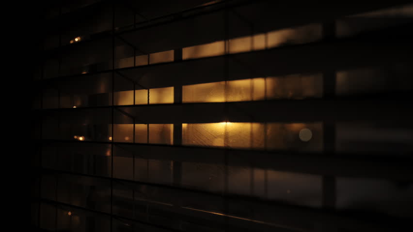 Looking at golden sunset through window closed by blinds. Close up footage