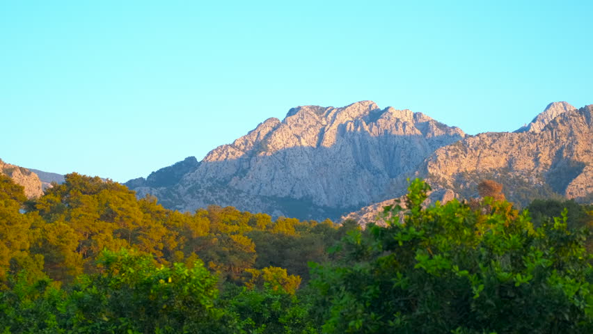 Majestic mountain range bathed in golden light at sunrise. Golden sunlight casting long shadows across mountain slopes during breathtaking sunrise