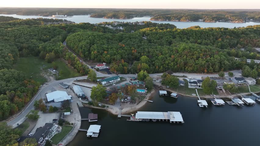Aerial view, flying over the river, forest, small houses on the water and hotels. Sunset Missouri, Ozark In summer, green trees, landscape. Drone 4K