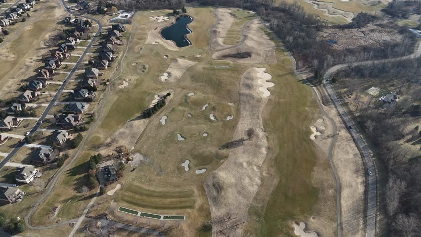 Drone aerial View Golf Course backed by subdivision. Springtime Golf. Sand traps and chipping range.