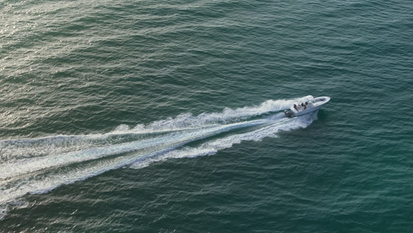 A vibrant aerial photo captures a boat racing across Floridas calm waters at sunrise, blending natures serenity with the vessels exhilarating motion in a stunning visual