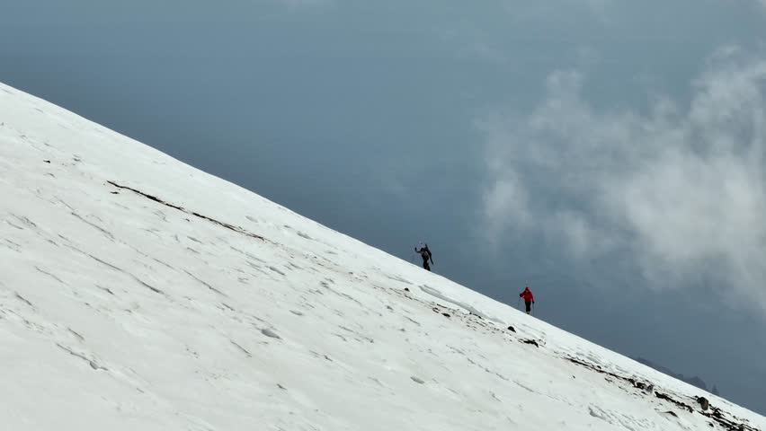 Group of mountain tourists climb snowy mountains in winter, aerial view