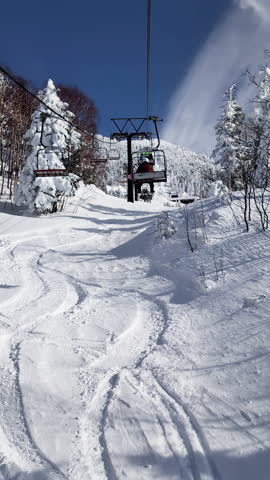 POV ski chairlift through snow covered forest. Vertical handheld shot