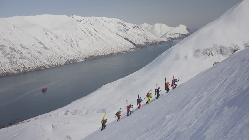 Group of mountain tourists climb snowy mountains in winter, aerial view