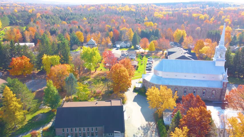 Historic church surrounded by fall foliage drone view in Estrie, Québec, Canada.