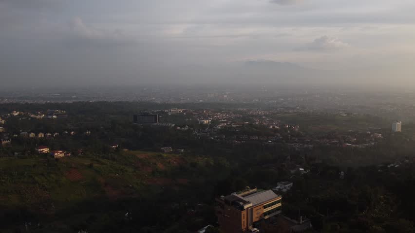 Sweeping aerial Drone view of green fields in Bandung surrounded by rolling hills and tranquil scenery in West Java Indonesia.