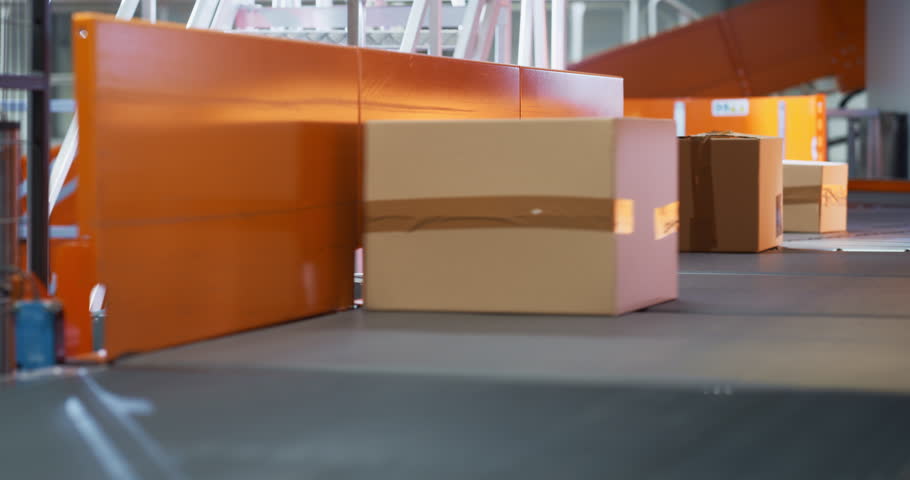 Cardboard Parcels, Boxes, Packages are Transported on an Automated Conveyor Line in a Busy Sorting Center at a Postal Service Warehouse. Concept of Logistics and Postal Service Operations