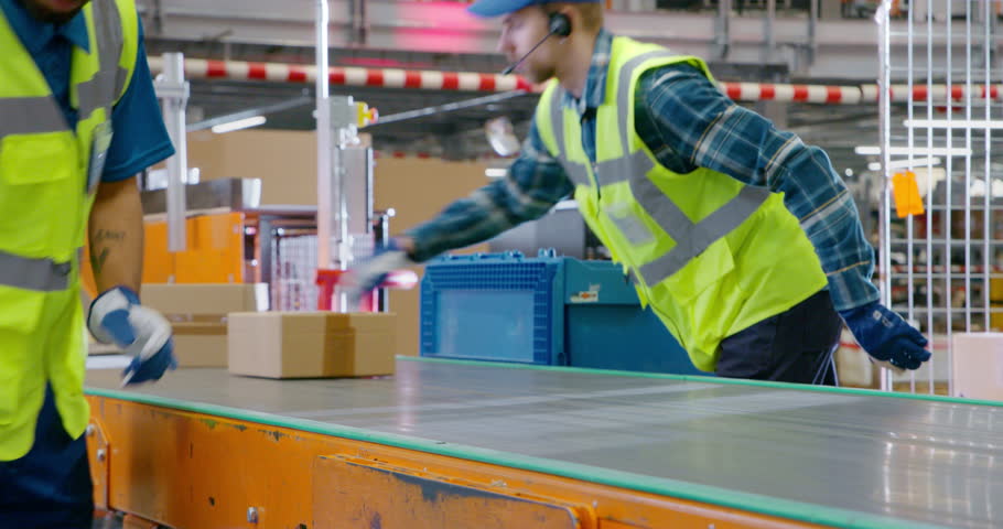 Close Up of Factory Employees Placing Boxes with Products on an Automated Production Line, Moving Goods in a Logistics Center. Workers Preparing Items for Delivery to Customers and Subscribers