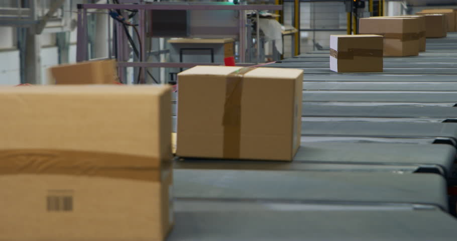 Cardboard Parcels, Boxes, Packages are Transported on an Automated Conveyor Line in a Busy Sorting Center at a Postal Service Warehouse. Concept of Logistics and Shipping Operations